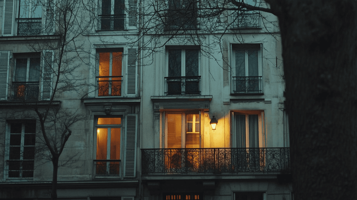 Façade d'immeuble ancien aux fenêtres éclairées à la tombée du jour, illustrant l'investissement locatif dans l'ancien